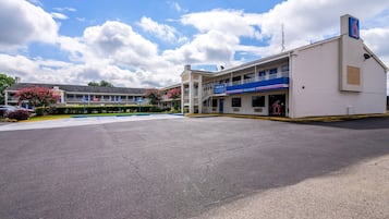 Un motel de dos pisos, con estacionamiento y cielo despejado.
