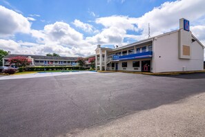 A motel with a two-story structure, a parking lot, and a clear sky.