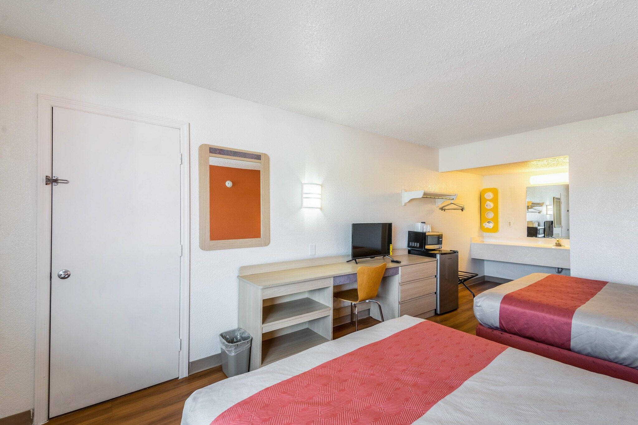 Una camera d'albergo con un letto, una scrivania, una sedia, una TV e un angolo cottura.