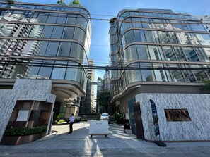 A modern building with curved glass facades and a central entrance. - 6 Star Luxury at The Heart of Bangkok (Watthana)