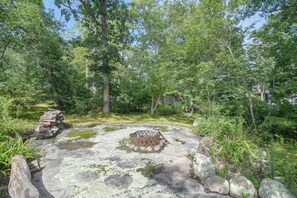 A natural outdoor area with a stone bench surrounded by trees and greenery. - Fire Pit, Deck! Rural Retreat Near East Beach (Charlestown)