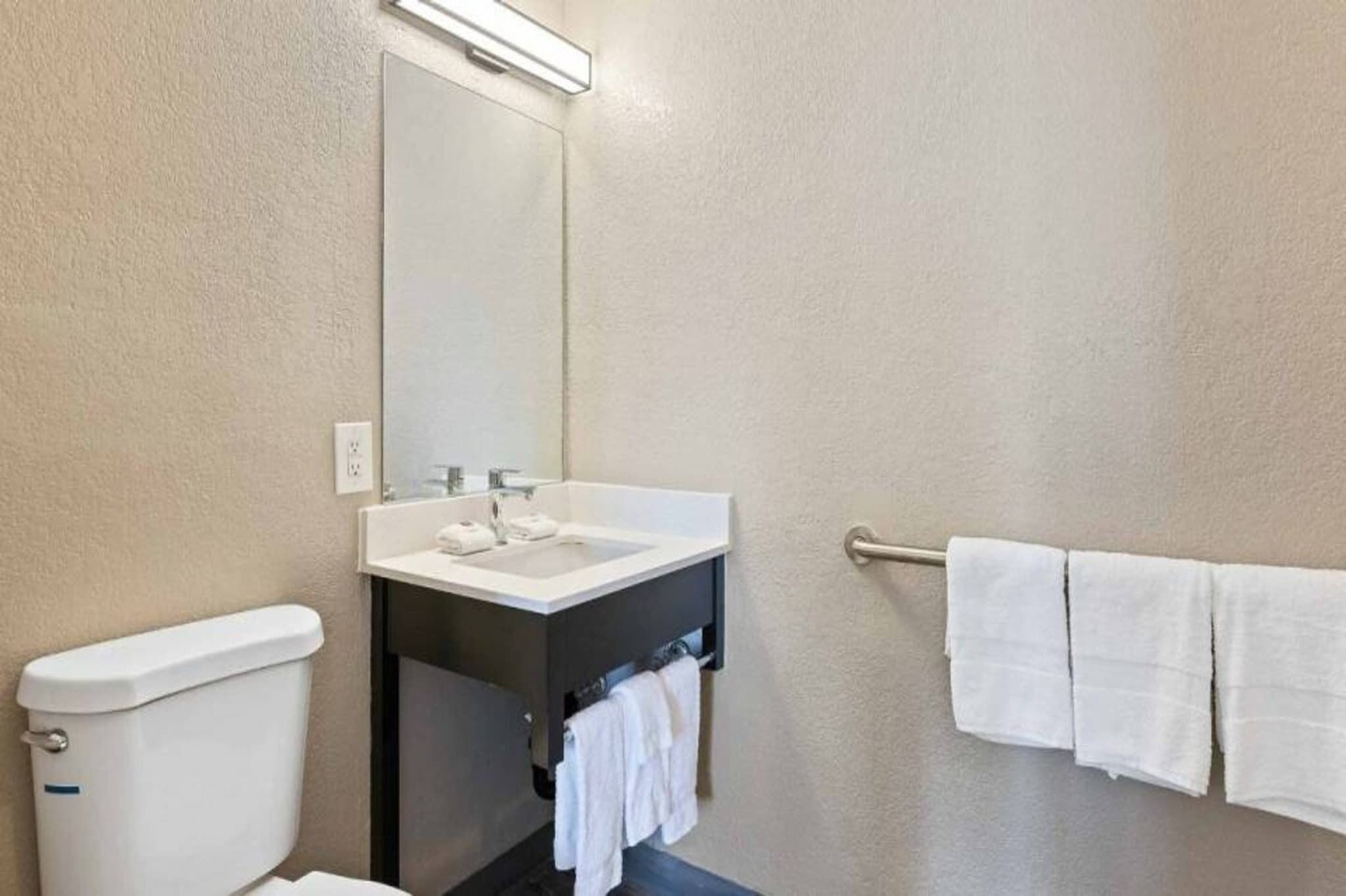 A bathroom with a toilet, sink, and towel rack.