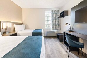 Habitación de hotel con dos camas, un escritorio, una silla, un televisor y una ventana con cortinas.