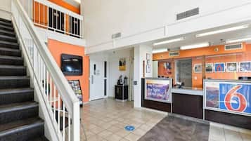 A hotel lobby with a reception desk, a staircase, and a tiled floor.