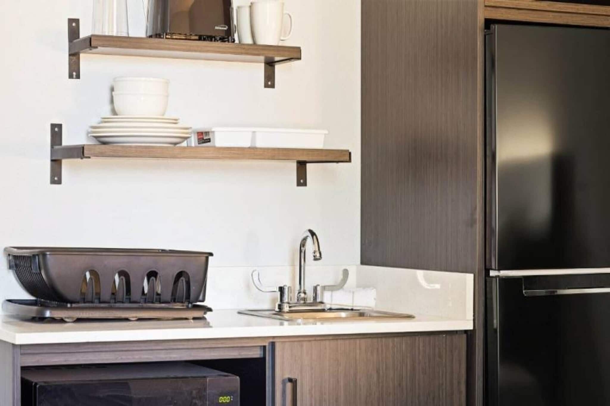 A kitchen with a built-in oven, a sink, and a stainless steel refrigerator.