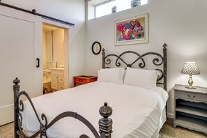 A bedroom with a bed, a nightstand, a dresser, a mirror, and a window.