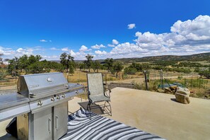 Un patio exterior con una parrilla, un tapete a rayas y vistas a un paisaje montañoso.