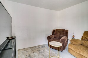 A room with a brown armchair, a small round table, and a sofa.