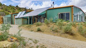 Uma casa moderna com painéis solares, uma janela ampla e fachada verde.