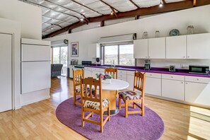 A modern kitchen with a dining area, featuring a round table, wooden chairs, and a purple rug.