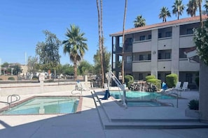 Un hotel con zona de piscina, incluyendo dos piscinas y sillones de descanso.