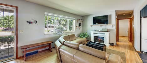 Una sala de estar moderna con un sofá de cuero, una chimenea, un televisor y un comedor con un banco.