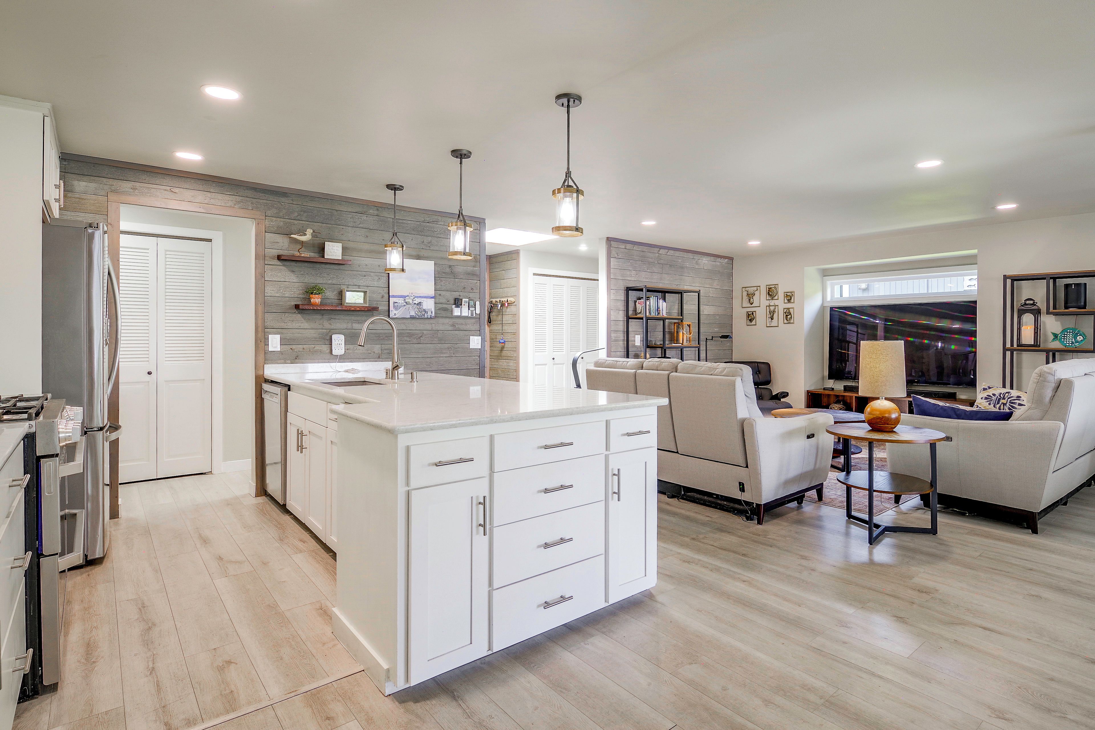 A modern kitchen with a central island, white cabinetry, and pendant lighting.