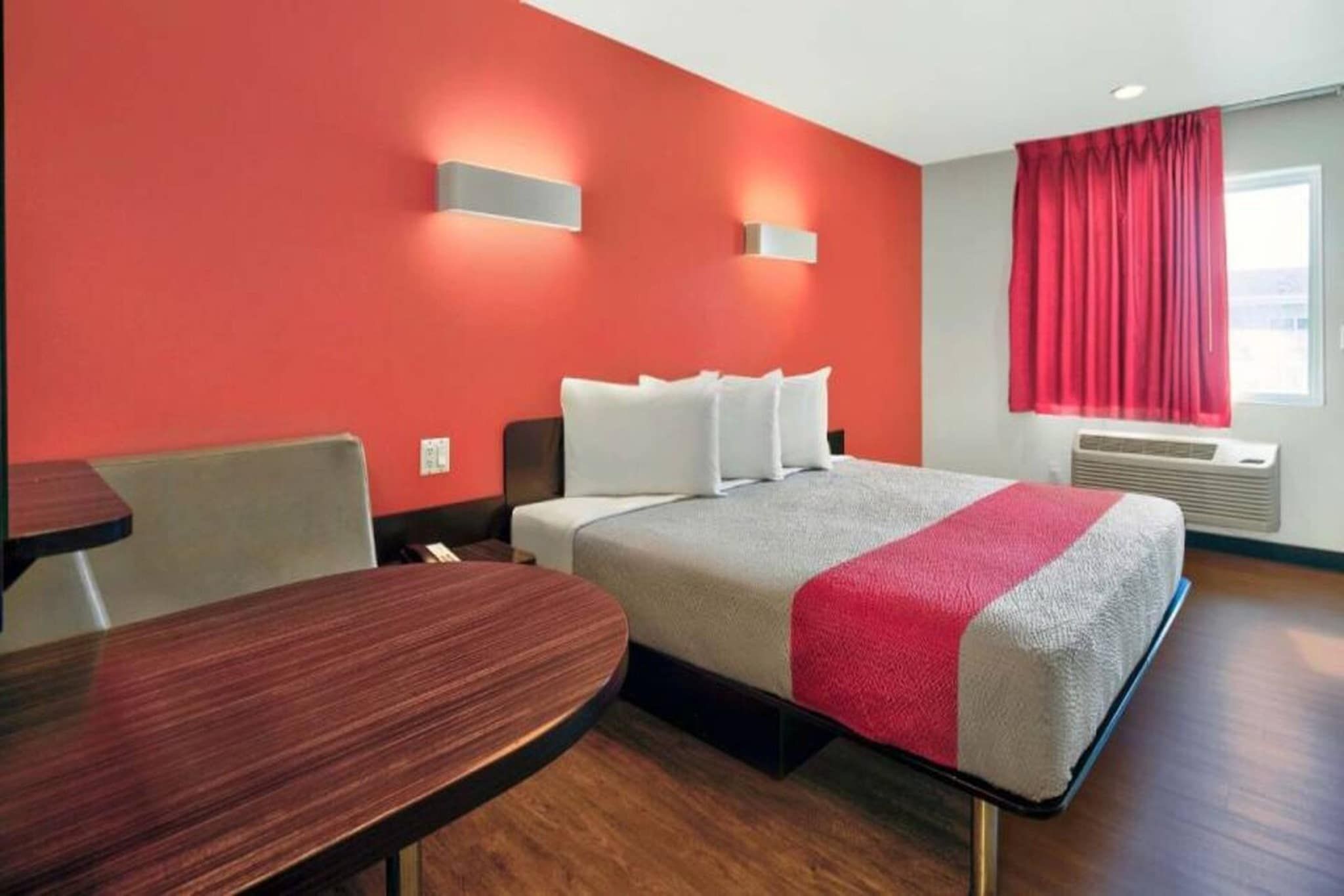Une chambre d’hôtel avec un lit, un bureau et une fenêtre avec des rideaux.