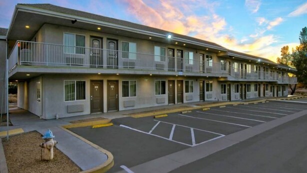 A motel with a parking lot, multiple entry doors, and a fire hydrant. - MS6 Victorville|1 King Bed|NS (VICTORVILLE)