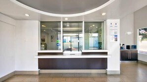 A reception area with a curved counter, glass doors, and a view into the interior. - MS6 Victorville|1 King Bed|NS (VICTORVILLE)