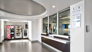 A modern reception area with a counter, vending machines, and a glass door leading to the interior. - 1 King Bed|Smoking|Victorville (VICTORVILLE)
