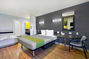 Een moderne hotelkamer met een bed, nachtkastje, stoel en een klein bureau met spiegel.
