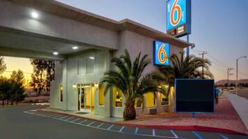 A 6 studio hotel with a parking lot and a building entrance.