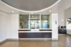 Uma área de recepção com balcão curvo, portas de vidro e vista para o interior.