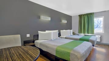Hotellihuone, jossa on kaksi sänkyä, pieni pöytä ja näkymä ulos.