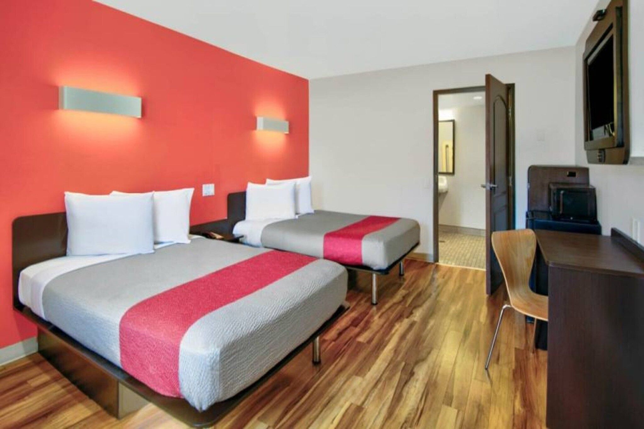Een hotelkamer met twee bedden, een bureau, een stoel en een televisie.