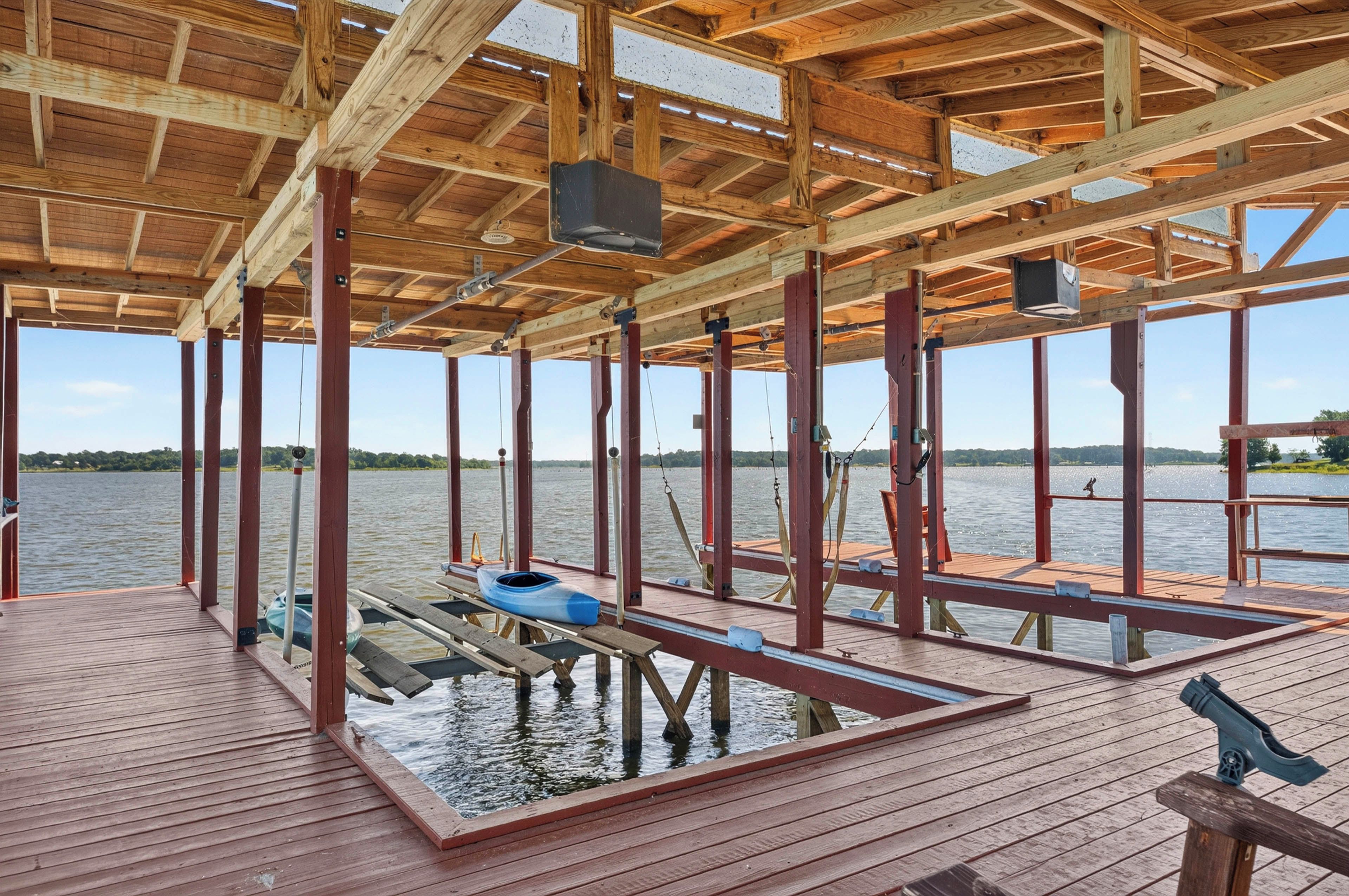 A wooden deck with a clear view of a lake, a canoe, and a bench.