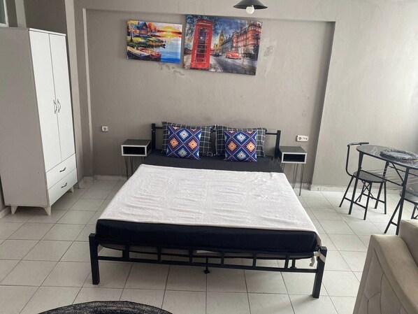 Ein Schlafzimmer mit einem Bett, Nachttischen, einem Kleiderschrank, einem kleinen Tisch mit Stühlen und zwei Bildern an der Wand.