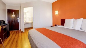 A hotel room with a bed, a desk, and a bathroom visible through an open door. - 1 QUEEN BED | NON-SMOKING (Benson)
