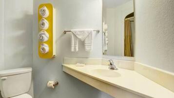 Ein Badezimmer mit Toilette, Waschbecken, Spiegel, Handtuchhalter und einer Toilettenpapierrolle.