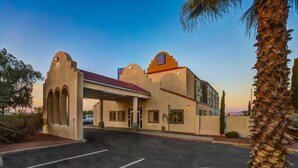 A hotel with a distinctive architectural style, featuring arched entrances and a flat roof. - 1 QUEEN BED | NON-SMOKING (Benson)