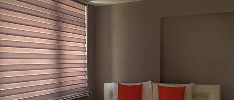 Ein Schlafzimmer mit einem großen Bett, einem Heizkörper und einem Fenster mit Jalousien.