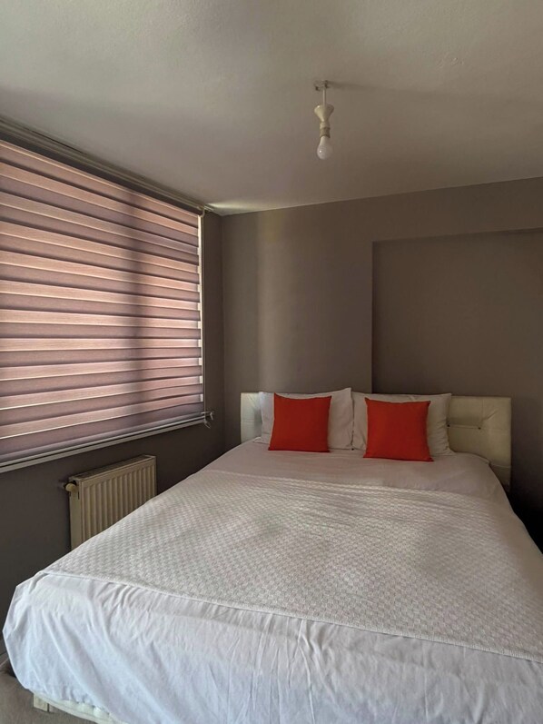 A bedroom with a large bed, a radiator, and a window with blinds. - 2-Bedroom Apartment in Central Pendik, Turkey (Pendik)