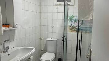 A bathroom with a white sink, toilet, and a shower with a glass door.
