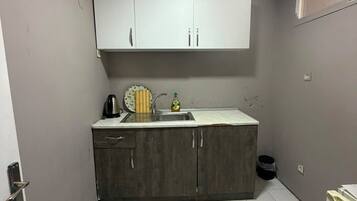 A small kitchen with white cabinets, a sink, and a tiled floor.