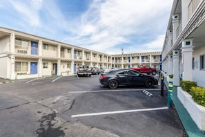 A parking lot with multiple cars, a building with balconies, and a clear sky. - 2 Full Beds | Non-Smoking (San Rafael)