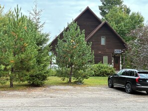 Ein Jagdhaus mit Steinfassade, einem Schotterweg und einem geparkten Geländewagen.