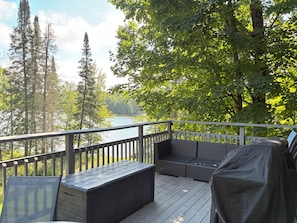 Una terraza con vistas a un lago, rodeada de árboles.