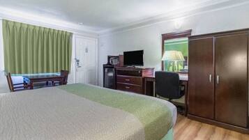 Een hotelkamer met een bed, een bureau, een stoel, een televisie en een kledingkast.