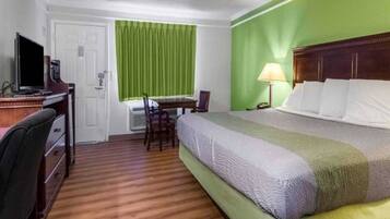 A hotel room with a bed, desk, chair, and a television.