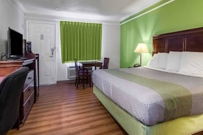 Una habitación de hotel con cama, escritorio, silla y televisor.
