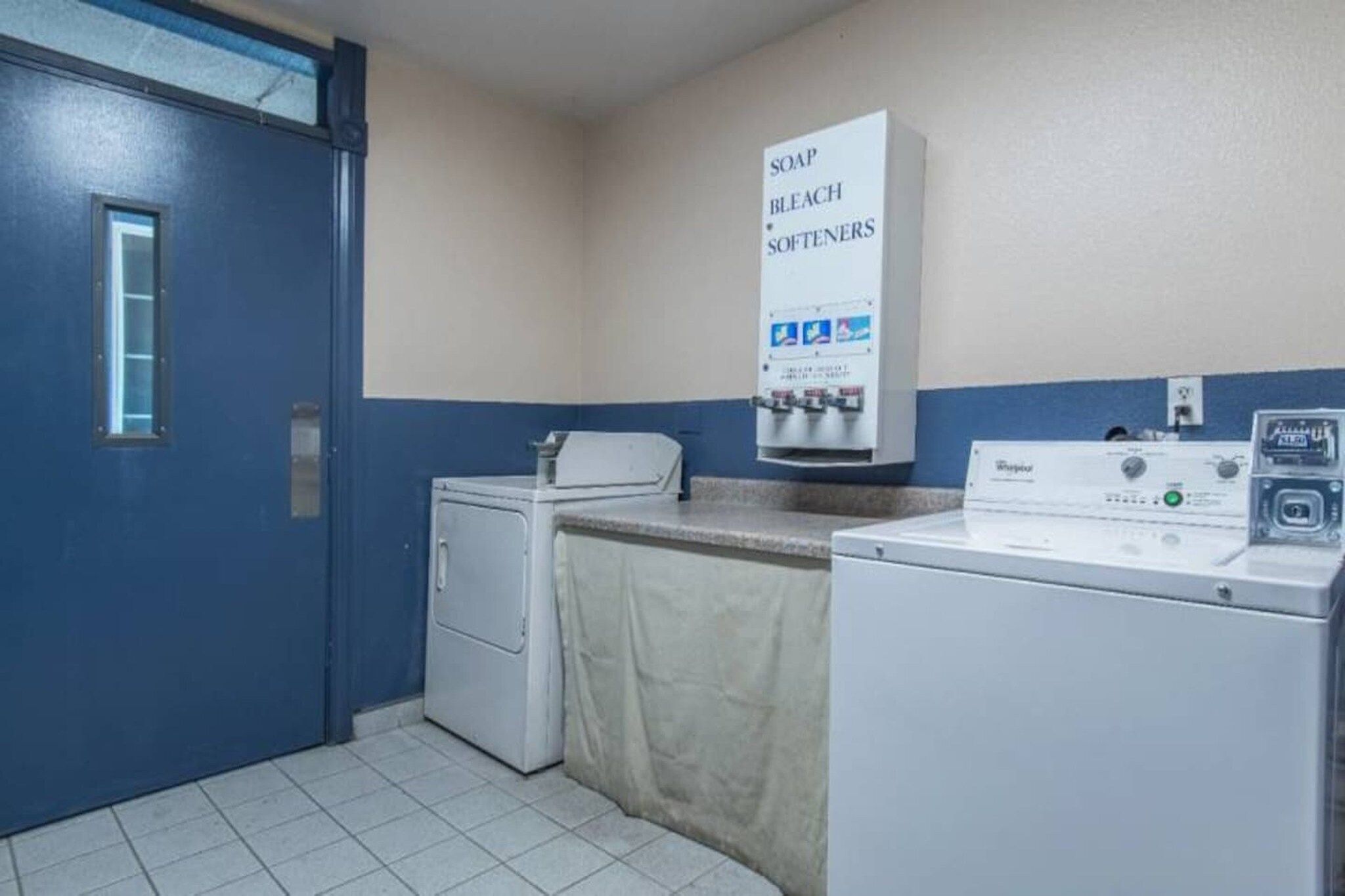 A laundry room with a washing machine, dryer, and a sign indicating the availability of soap, bleach, and softeners.