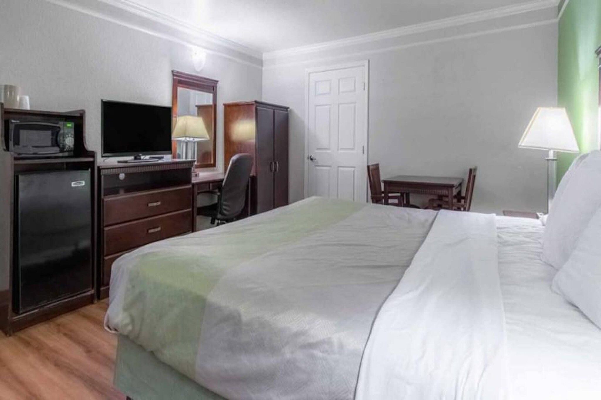 Une chambre d’hôtel comprenant un lit, un bureau avec une chaise, une télévision, une armoire et une porte.