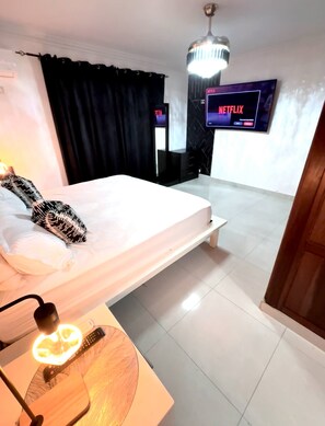 Une chambre d’hôtel avec un lit, un téléviseur fixé au mur et un luminaire au plafond.