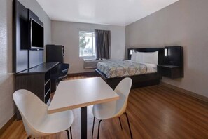 Una habitación de hotel con una cama, un televisor, un escritorio y dos sillas.