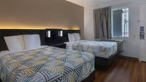 Una habitación de hotel con dos camas, una ventana con cortinas y un televisor montado en la pared.