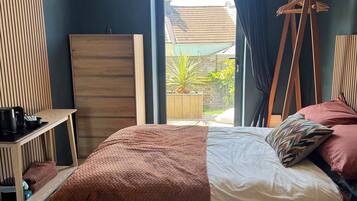 A bedroom with a bed, a wooden dresser, a hanging chair, and a view of the outside.