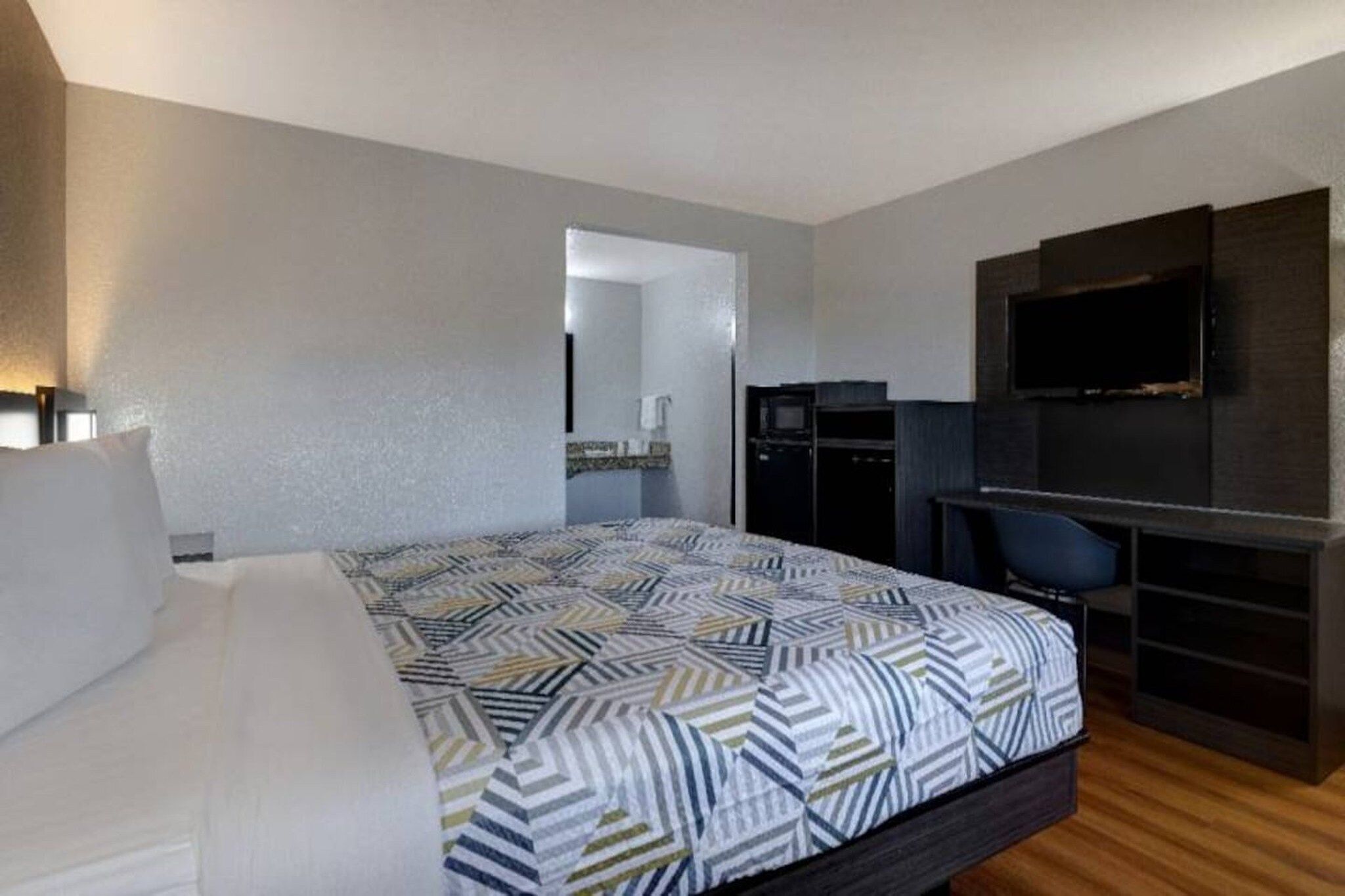 A hotel room with a bed, a desk, a television, and a mirror.