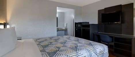 Une chambre d’hôtel avec un lit, un bureau, une télévision et un miroir.