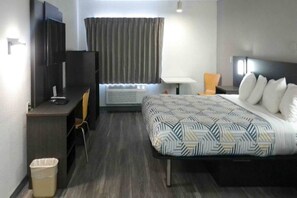 A hotel room with a bed, desk, chair, and a television. - 1 King Bed  Non-Smoking (Winslow)